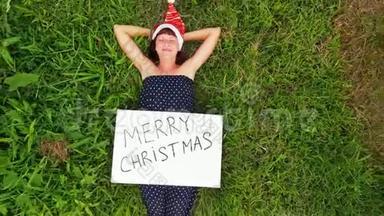 飞行无人机视频年轻女子与红色帽子和白板与手写文字圣诞快乐热带背景。